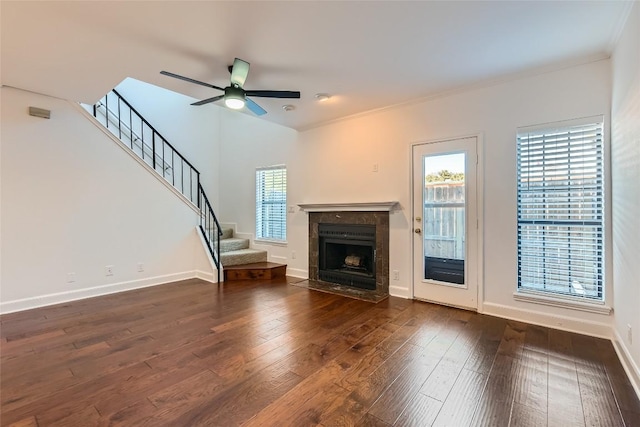 unfurnished living room featuring ceiling fan, ornamental molding, a high end fireplace, and dark hardwood / wood-style floors