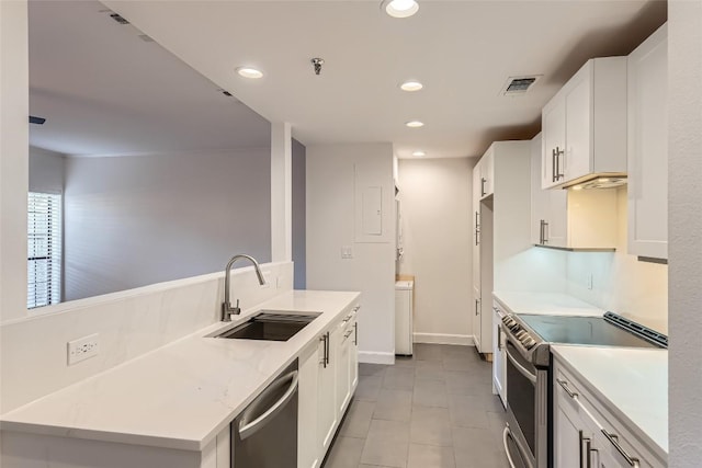 kitchen featuring appliances with stainless steel finishes, light stone countertops, light tile patterned floors, sink, and white cabinetry