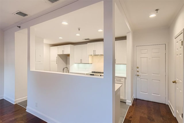 kitchen with white cabinets, tasteful backsplash, kitchen peninsula, and dark hardwood / wood-style floors