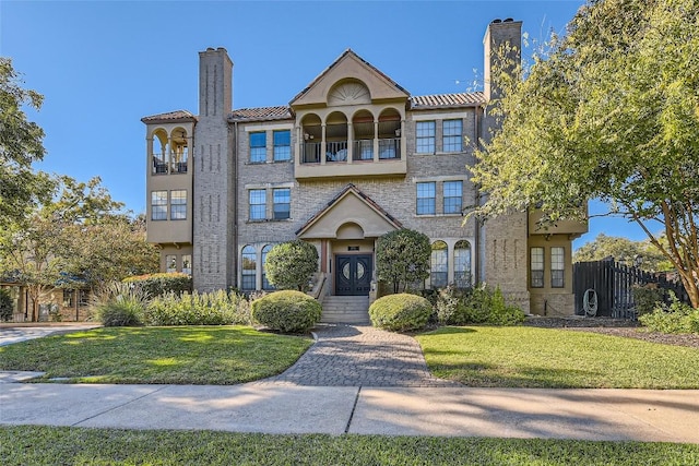 view of front facade with a front yard and a balcony