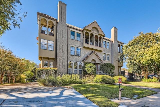 view of front of house with a balcony and a front lawn