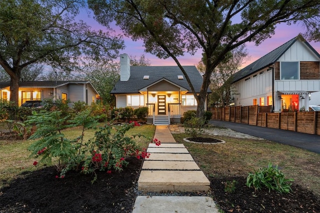 bungalow featuring a chimney, fence, and board and batten siding