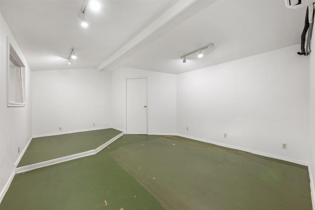 basement with baseboards and rail lighting