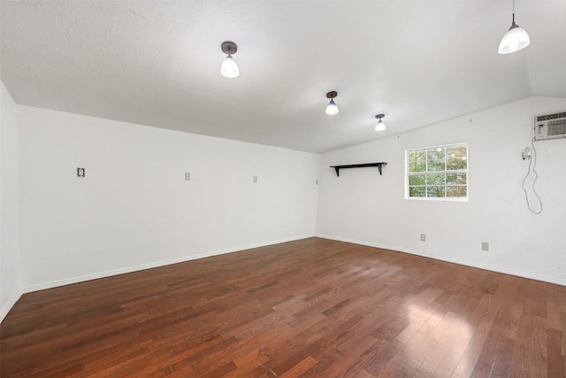 spare room with lofted ceiling, hardwood / wood-style flooring, baseboards, and a wall mounted air conditioner