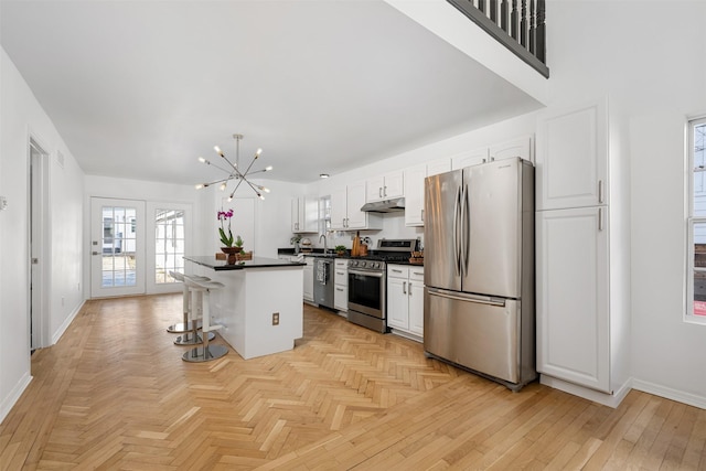 kitchen featuring white cabinetry, appliances with stainless steel finishes, a chandelier, a breakfast bar, and a center island