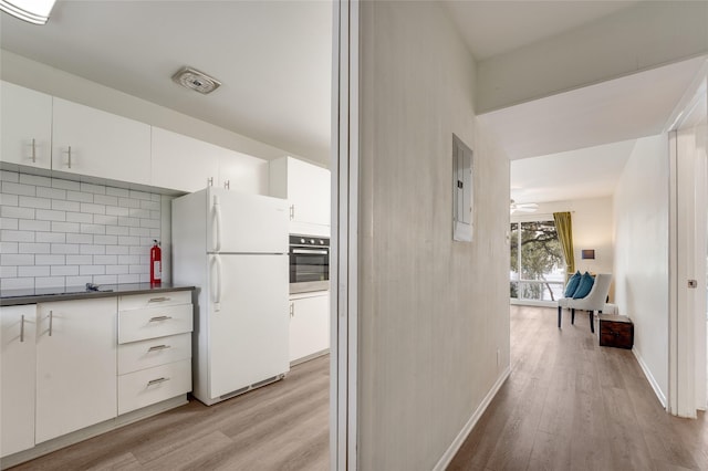 hallway with electric panel and light hardwood / wood-style flooring