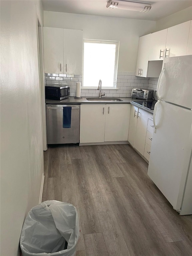 kitchen with white cabinetry, stainless steel appliances, backsplash, dark wood-type flooring, and sink