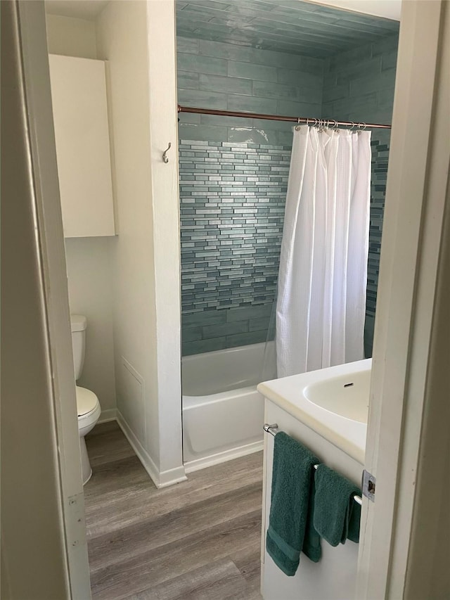 full bathroom with toilet, hardwood / wood-style flooring, vanity, and shower / bath combo with shower curtain