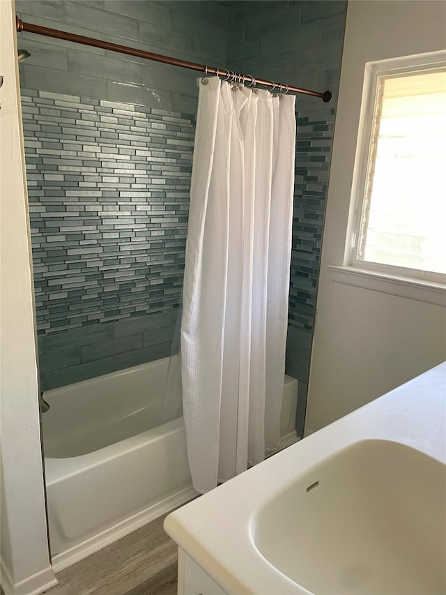 bathroom with hardwood / wood-style flooring, sink, and shower / bathtub combination with curtain