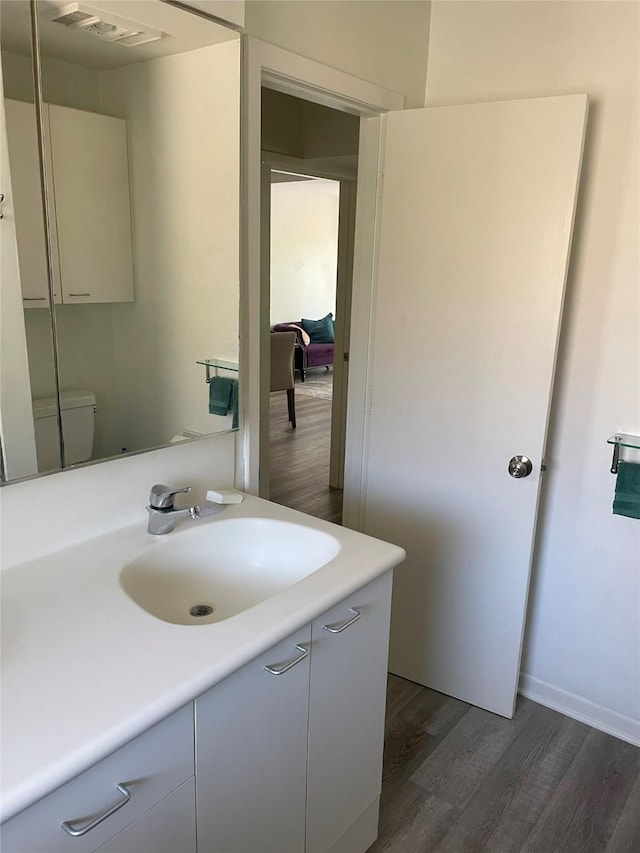 bathroom with toilet, hardwood / wood-style flooring, and vanity