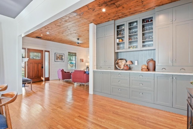 bar featuring gray cabinetry, light hardwood / wood-style floors, and wooden ceiling