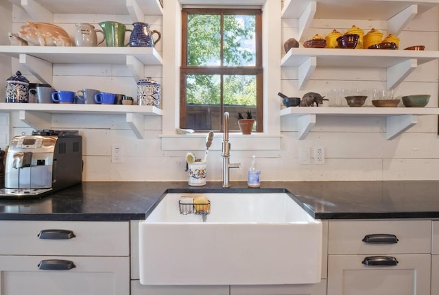 kitchen with tasteful backsplash, white cabinetry, and sink