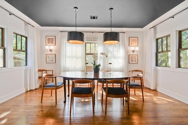 dining area with crown molding, plenty of natural light, and hardwood / wood-style floors