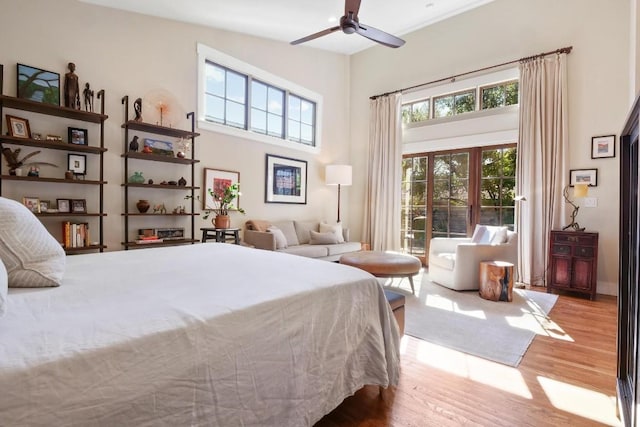 bedroom featuring ceiling fan, a towering ceiling, and light wood-type flooring