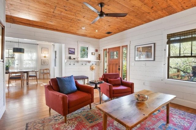 living room with ceiling fan, wooden walls, light hardwood / wood-style flooring, and wooden ceiling