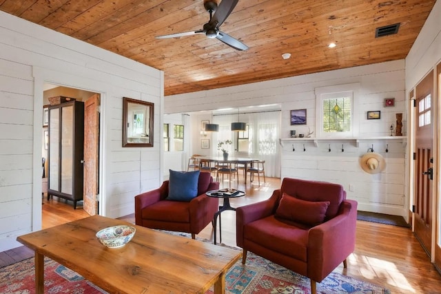 living room with wooden ceiling, light hardwood / wood-style floors, ceiling fan, and wood walls