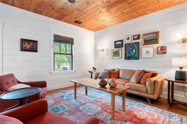 living area with visible vents, wooden ceiling, wood finished floors, and wooden walls