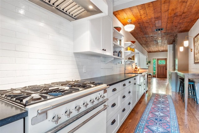 kitchen featuring dark countertops, range with gas stovetop, open shelves, hardwood / wood-style floors, and white cabinetry