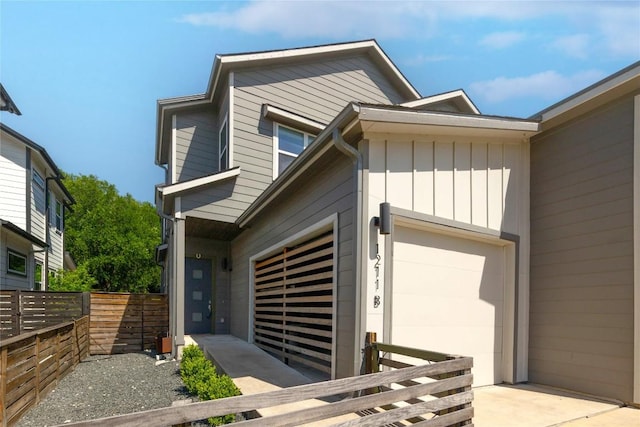 view of front facade featuring a garage, board and batten siding, fence, and concrete driveway
