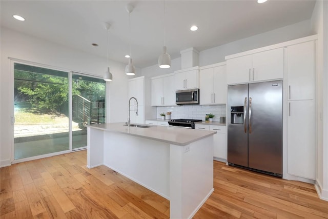 1211 Cometa St Unit B, Austin, TX 78721 - kitchen featuring stainless steel appliances, a sink, decorative backsplash, light wood-style flooring, and a kitchen island with sink