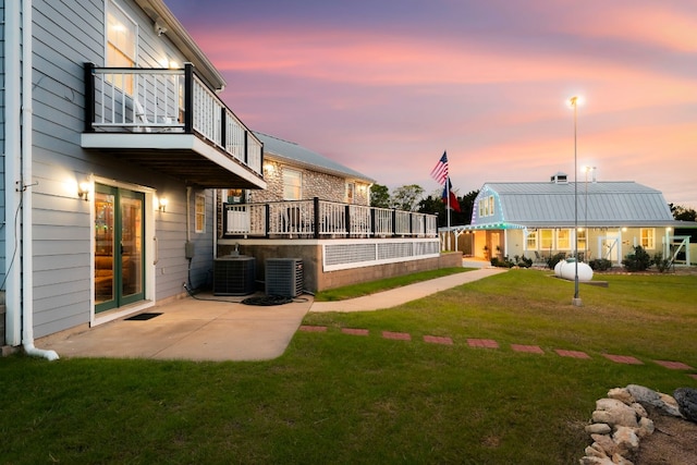 yard at dusk with a patio, a balcony, and central AC unit