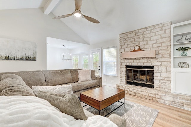 living room with a stone fireplace, high vaulted ceiling, hardwood / wood-style flooring, built in features, and beamed ceiling