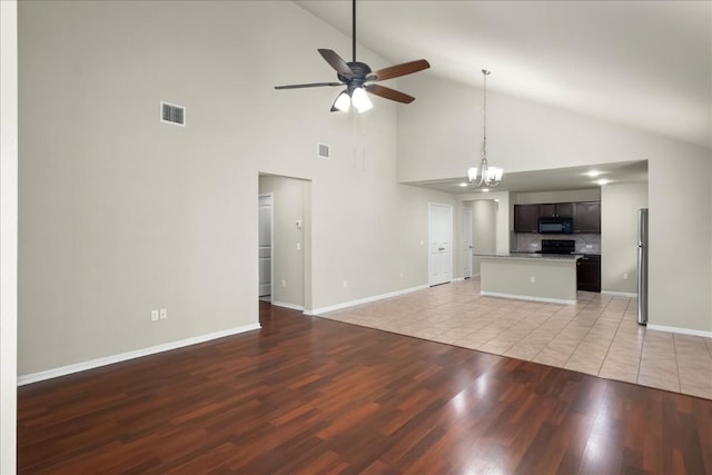 unfurnished living room with high vaulted ceiling, ceiling fan with notable chandelier, and light wood-type flooring