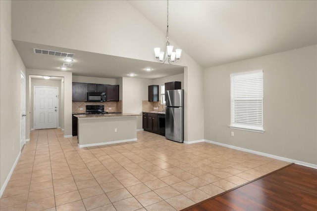 kitchen with hanging light fixtures, backsplash, a chandelier, light tile patterned floors, and black appliances