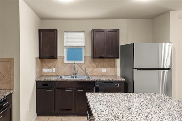 kitchen with dishwasher, backsplash, sink, light tile patterned floors, and stainless steel refrigerator