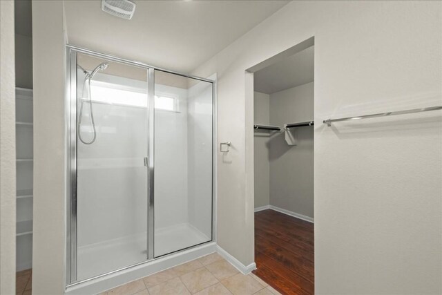 bathroom with wood-type flooring and an enclosed shower