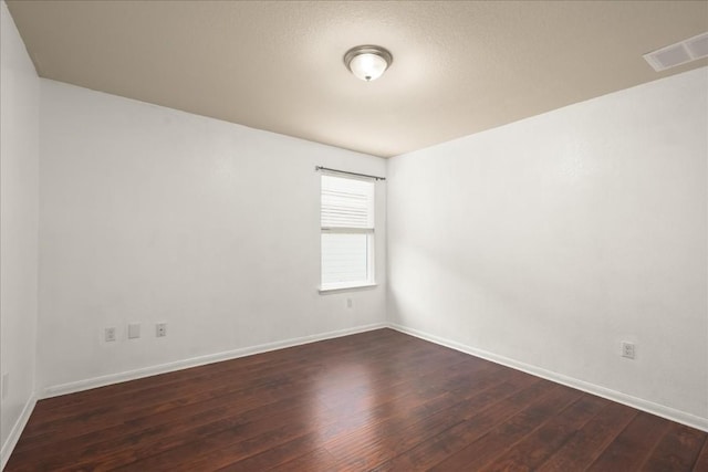 empty room featuring a textured ceiling and dark wood-type flooring