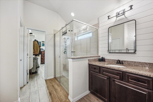 bathroom featuring a shower with door, vanity, lofted ceiling, and hardwood / wood-style flooring