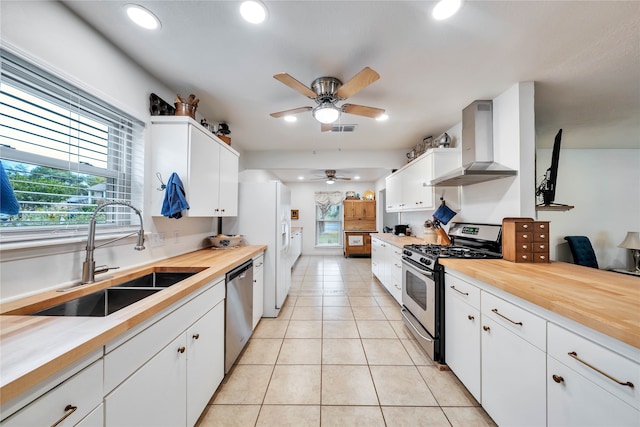 kitchen with appliances with stainless steel finishes, sink, wall chimney range hood, and white cabinets