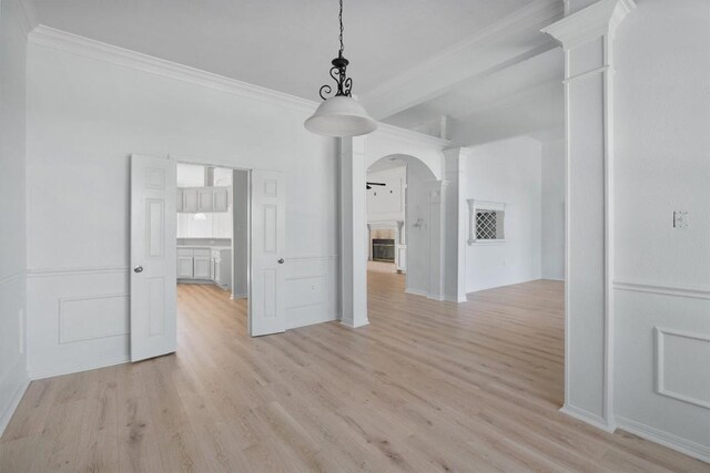 unfurnished dining area featuring decorative columns, crown molding, and light hardwood / wood-style floors