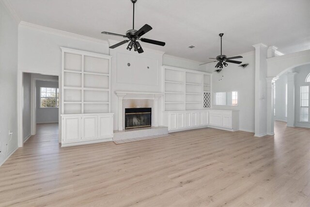 unfurnished living room with a tiled fireplace, ceiling fan, ornamental molding, and light wood-type flooring