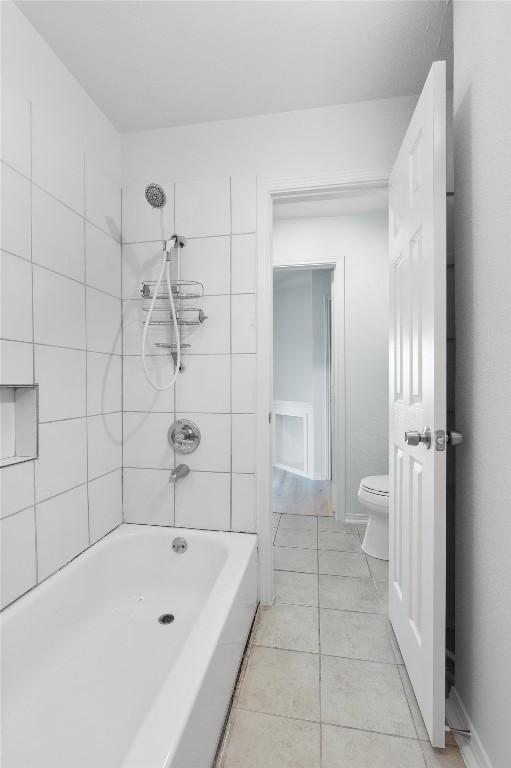 bathroom with tile patterned floors, toilet, and tiled shower / bath