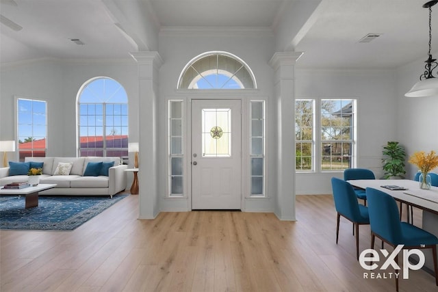 foyer entrance with decorative columns, crown molding, and light hardwood / wood-style floors