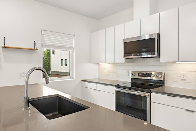 kitchen with white cabinetry, appliances with stainless steel finishes, sink, and backsplash