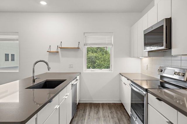 kitchen with sink, white cabinetry, appliances with stainless steel finishes, hardwood / wood-style floors, and decorative backsplash