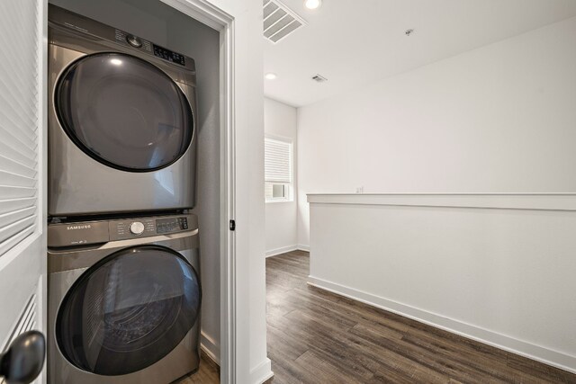 laundry room featuring dark wood-type flooring and stacked washer and clothes dryer