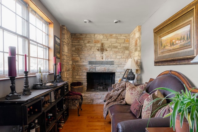 sitting room with a stone fireplace and wood-type flooring