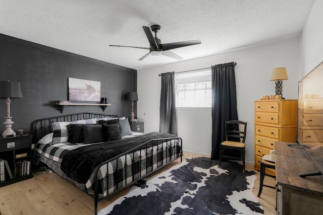 bedroom with a textured ceiling, ceiling fan, and light hardwood / wood-style flooring