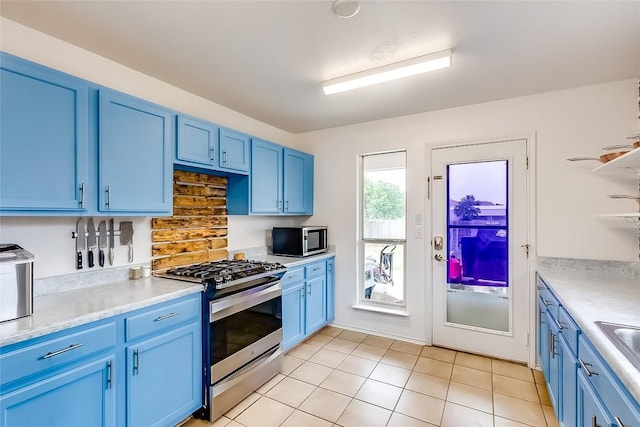 kitchen with light tile patterned floors, stainless steel appliances, blue cabinets, and sink