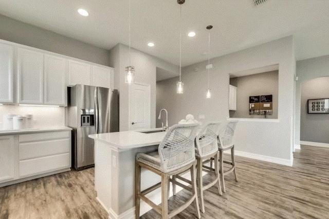 kitchen with decorative light fixtures, white cabinetry, stainless steel refrigerator with ice dispenser, and light hardwood / wood-style flooring