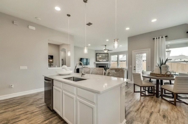 kitchen featuring dishwasher, a center island with sink, sink, hardwood / wood-style flooring, and white cabinetry