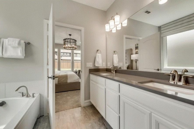 bathroom with hardwood / wood-style floors, vanity, a bathtub, and a chandelier