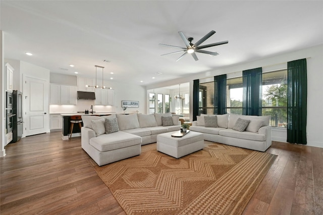 living room with sink, ceiling fan with notable chandelier, and hardwood / wood-style flooring