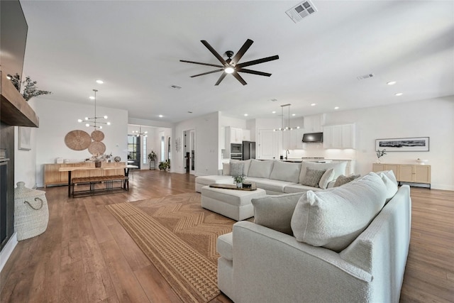 living room with light hardwood / wood-style flooring, ceiling fan with notable chandelier, and sink