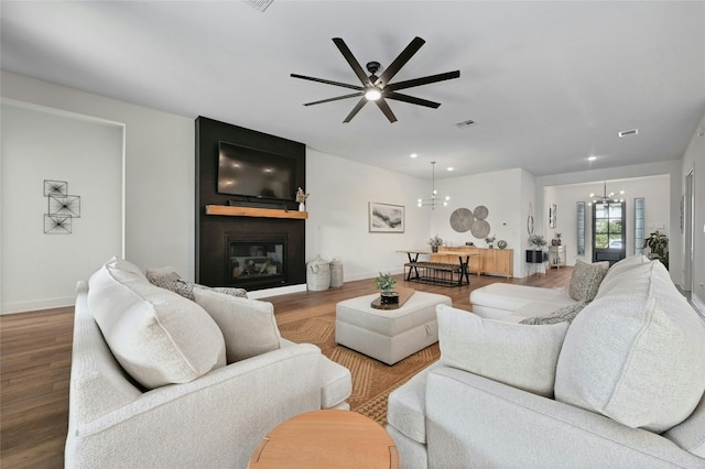 living room featuring a fireplace, ceiling fan with notable chandelier, and hardwood / wood-style flooring