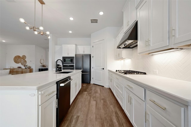 kitchen with a center island with sink, white cabinetry, hardwood / wood-style floors, and appliances with stainless steel finishes